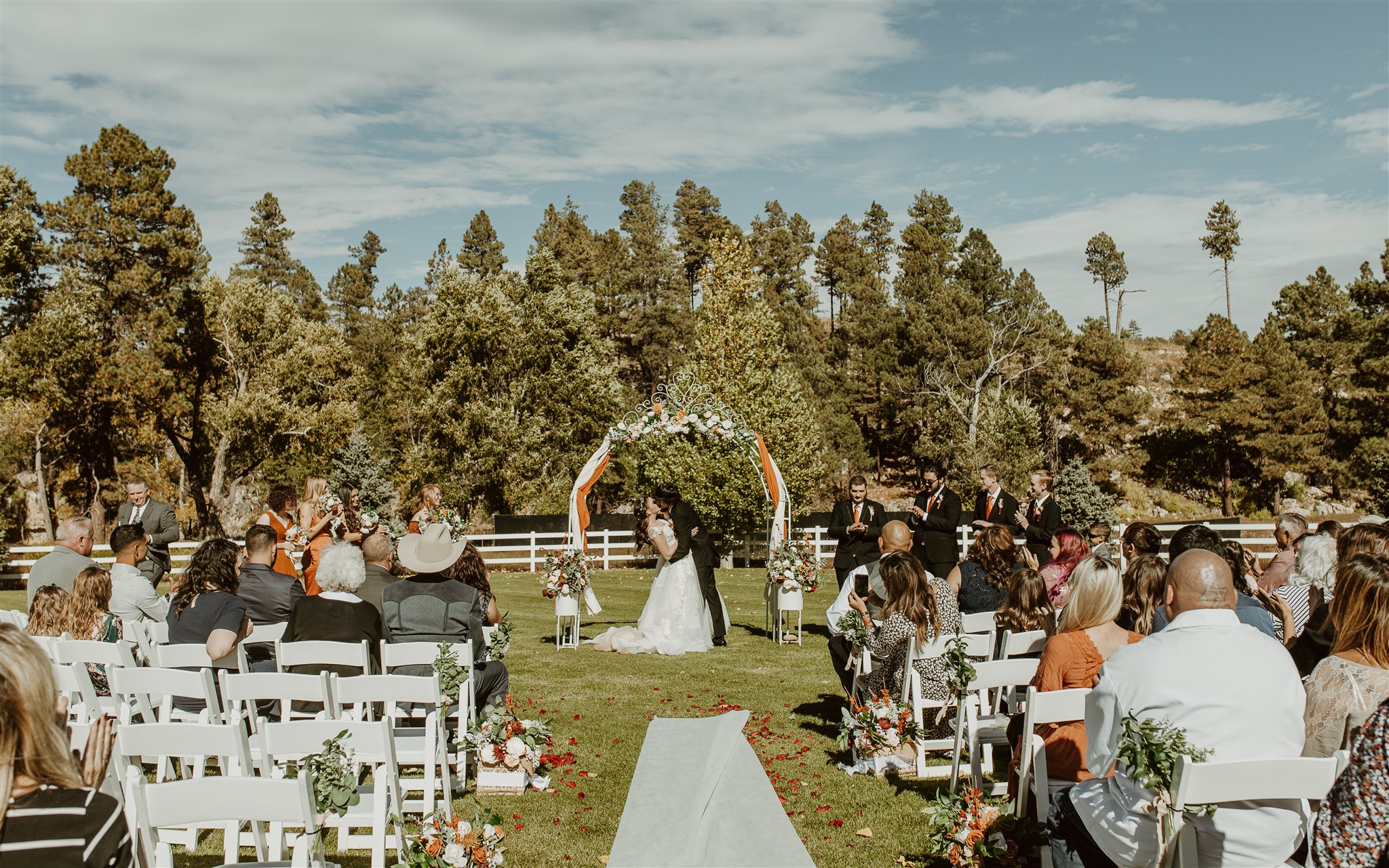 A groom dips and kisses his bride to end their outdoor garden ceremony