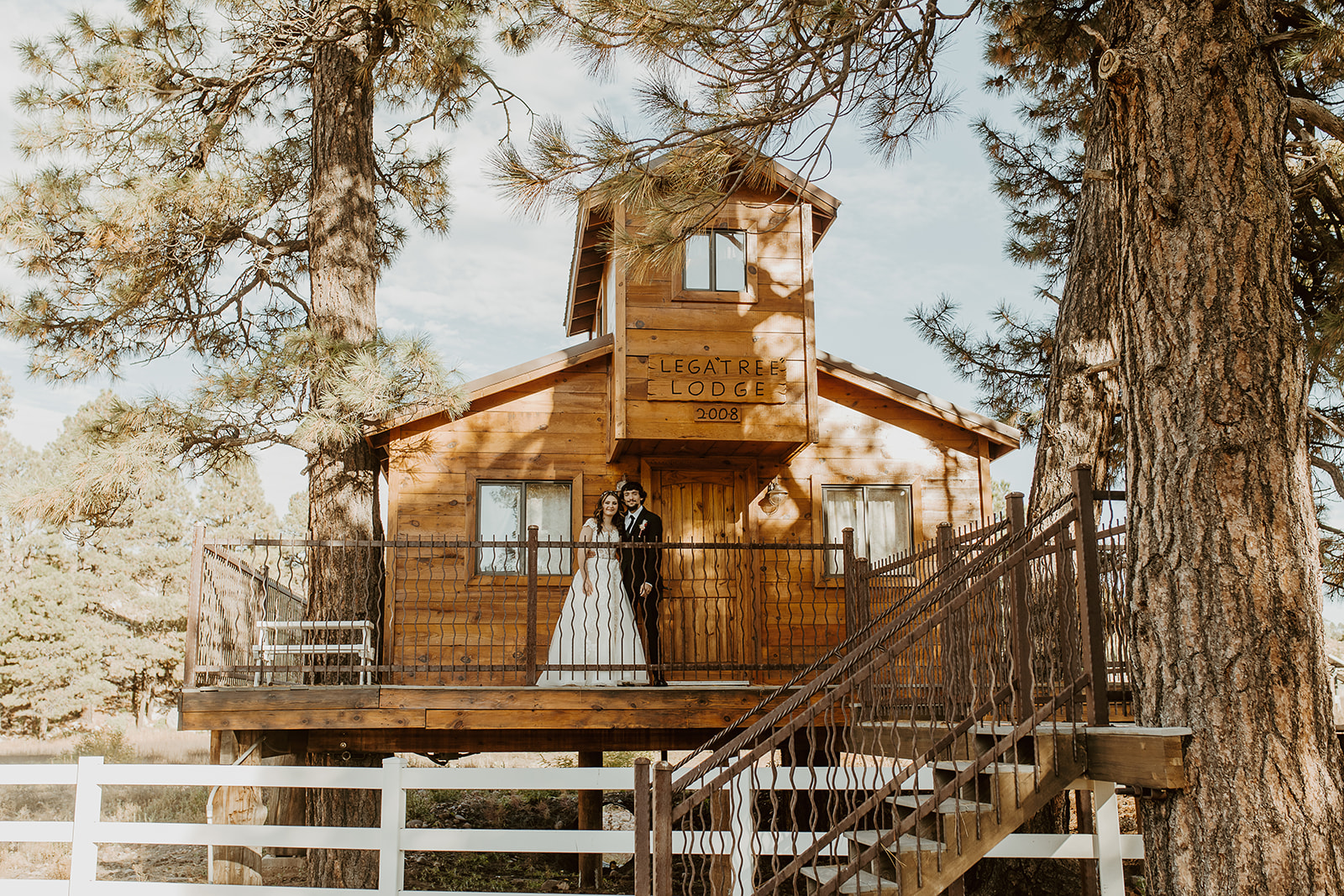 A bride and groom stand under the front porch sign of legacy lodge in Heber, AZ